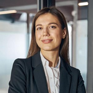 Front view of an attractive tranquil female employee with her arms folded standing in the office